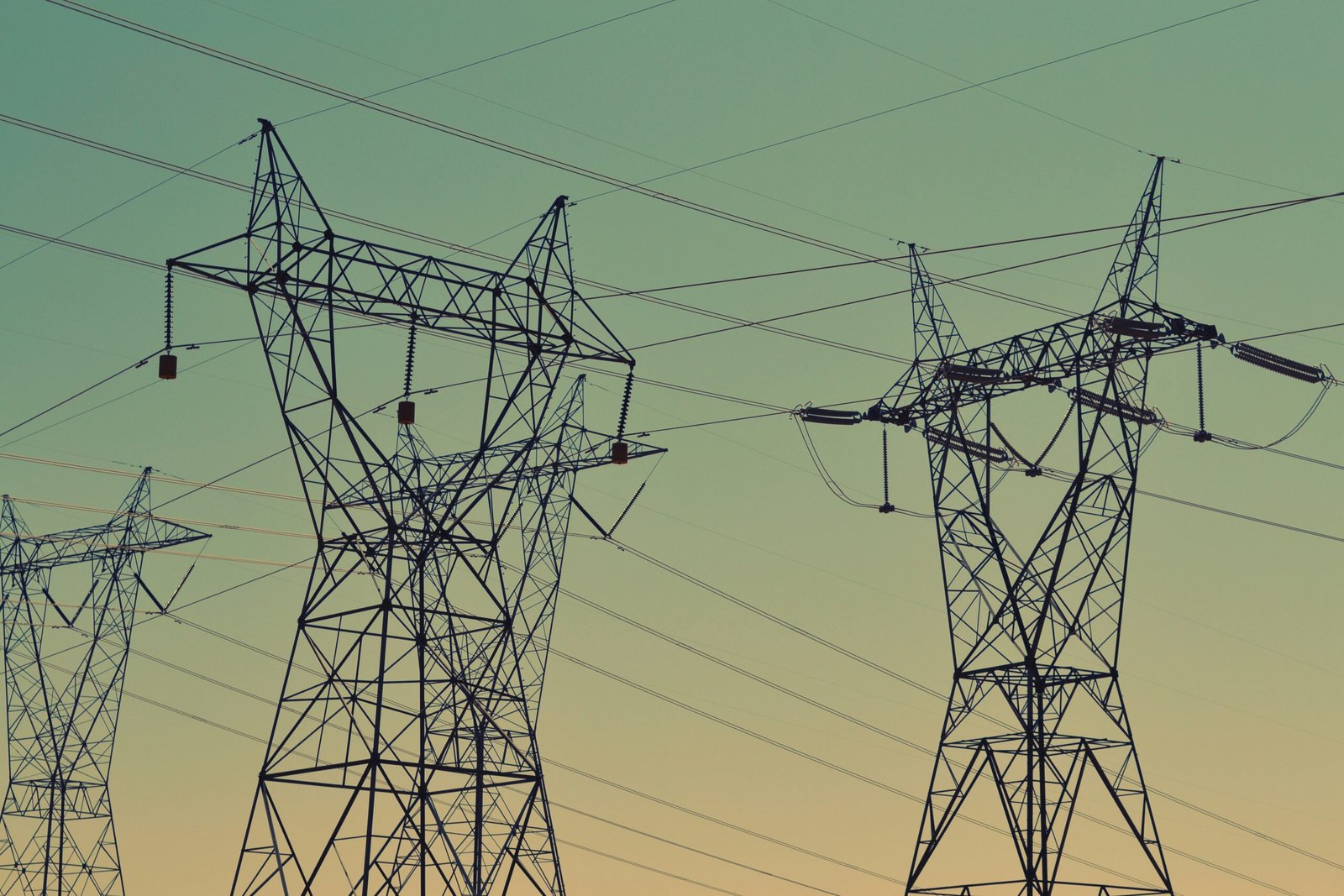 black transmission towers under green sky